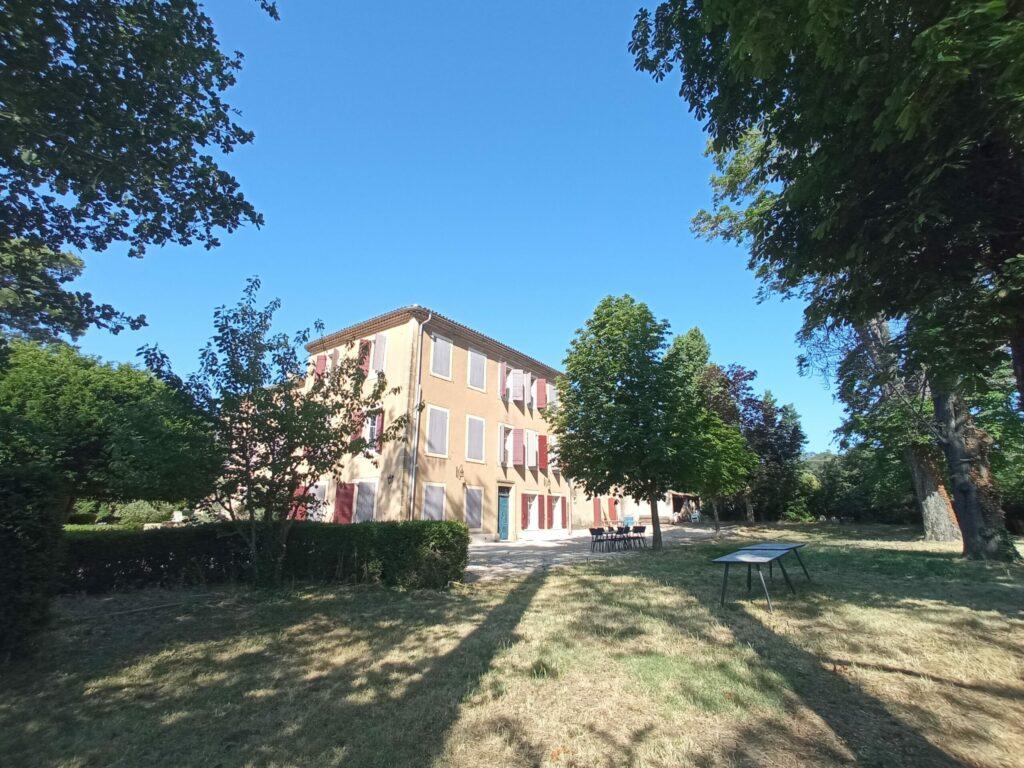 Vue extérieure de la façade principale de la bastide du Domaine de Ribbe avec ses nombreux volets et sa cour gravillonnée.